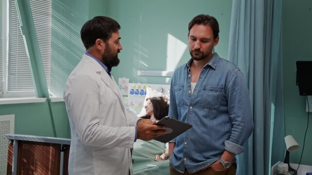 Doctor shows woman medical records to husband in clinic ward