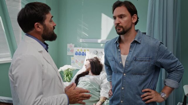 Doctor explains medical update to worried male visitor in ward