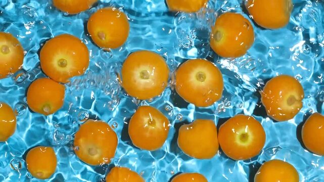 Fresh physalis berries in clean water with splashes, top view slow motion