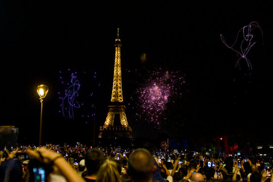 Dense crowd watches fireworks near a streetlamp by the Eiffel Tower in Paris France July 13 2026