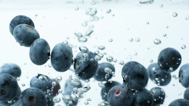 Macro of ripe blueberries falling into water in slow motion