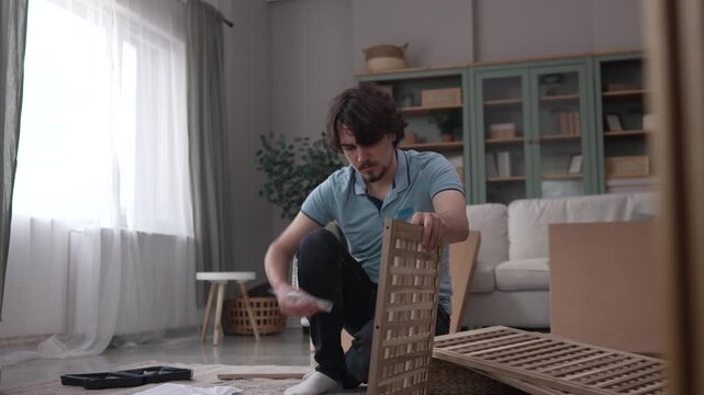 Focused man assembling wooden furniture in living room