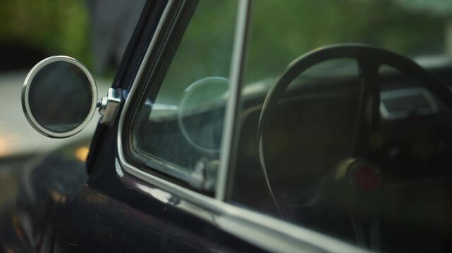 Detailed view of a classic car's chrome side mirror and window frame with soft reflections
