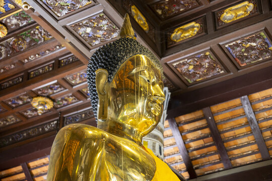 Golden Buddha statue in ornate temple interior conveying serene reverence and warm reflective light
