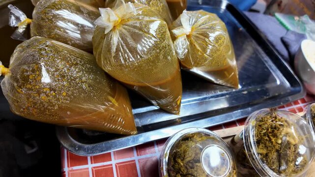 Close-up of traditional Thai curry soup packed in clear plastic bags for takeaway at a local street food market in Thailand. Authentic homemade curry prepared for customers using traditional street fo
