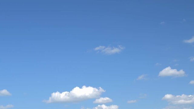 white clouds float across a bright blue sky on a sunny summer day