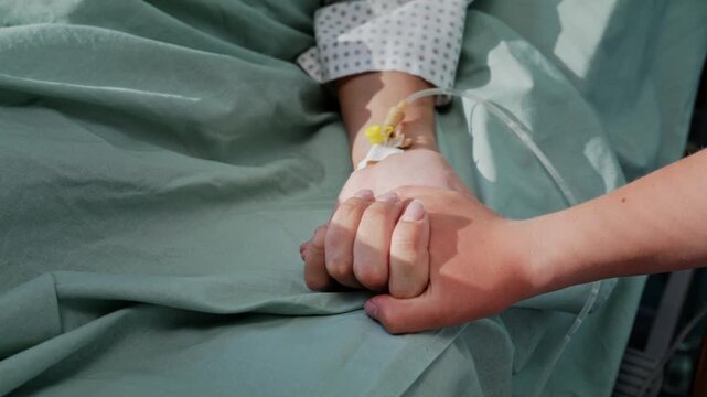 Young girl holds mother hand during quiet hospital recovery