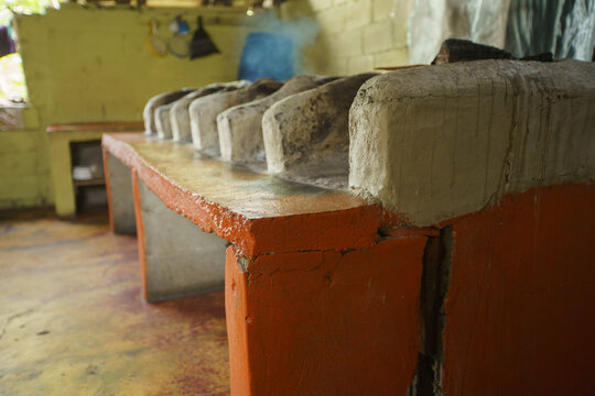 Indoor rural kitchen or fireplace setup with an old-fashioned concrete wood-burning cooktop