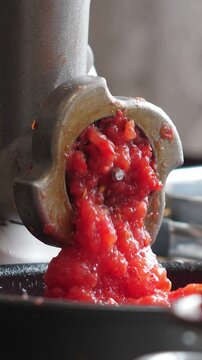 Cooking tomato paste in food grinding machine. Closeup. Vertical footage