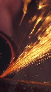 Sharpening axe with grinder in the dark with flying sparks. Vertical footage
