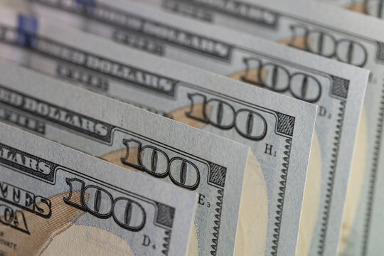 Close-up of US one hundred dollar bills stacked in rows with focus on 100 digit