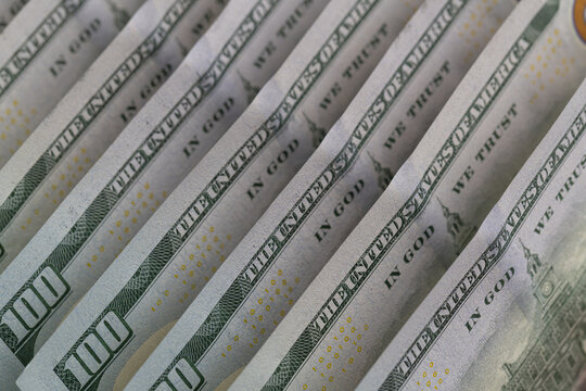 Macro shot of US dollar bills with repeating The United States of America text and selective focus