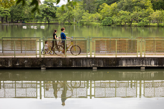 Happy Smiling father and mother with girl kid on bicycles having fun in city park. outdoor activitie with daughter father, mother and grandfather