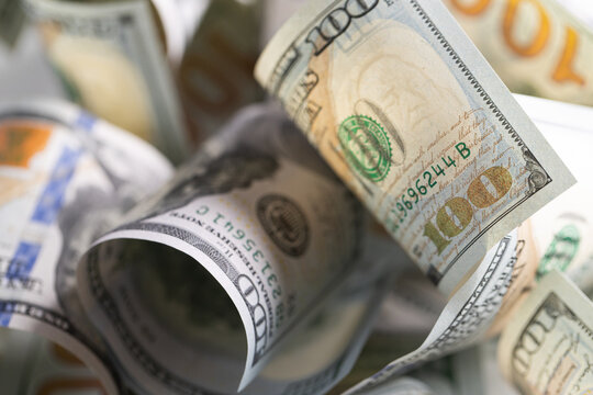 Close-up of scattered US one hundred dollar bills with selective focus on Benjamin Franklin portrait