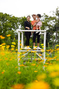 Mother and daughter walking hand in hand at spring park, moment of family bonding and togetherness. outdoor activitie. Asian Family with father mother daughter and grandfather