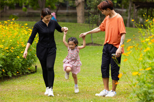 Mother and Father holding and jump up daughter in the air at spring park, moment of family bonding and togetherness. outdoor activitie. Asian Family with father mother daughter and grandfather