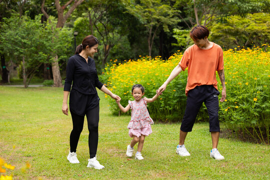 Mother and daughter walking hand in hand at spring park, moment of family bonding and togetherness. outdoor activitie. Asian Family with father mother daughter and grandfather