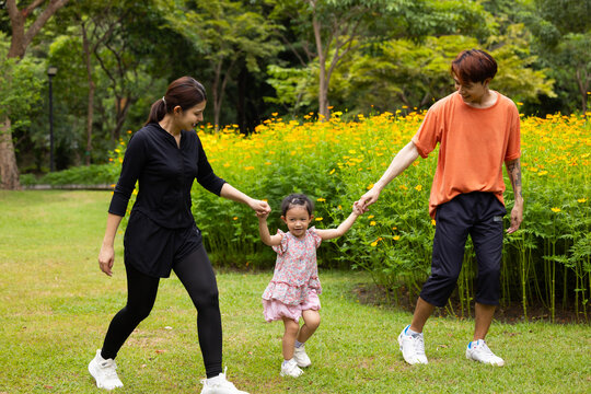 Mother and daughter walking hand in hand at spring park, moment of family bonding and togetherness. outdoor activitie. Asian Family with father mother daughter and grandfather