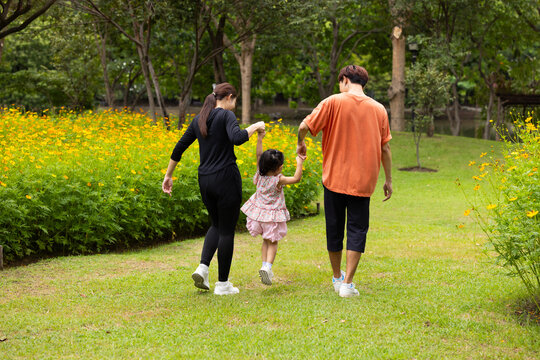Mother and Father holding and jump up daughter in the air at spring park, moment of family bonding and togetherness. outdoor activitie. Asian Family with father mother daughter and grandfather