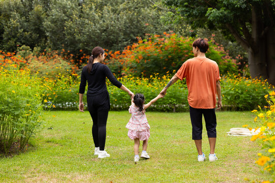 Mother and Father holding and jump up daughter in the air at spring park, moment of family bonding and togetherness. outdoor activitie. Asian Family with father mother daughter and grandfather