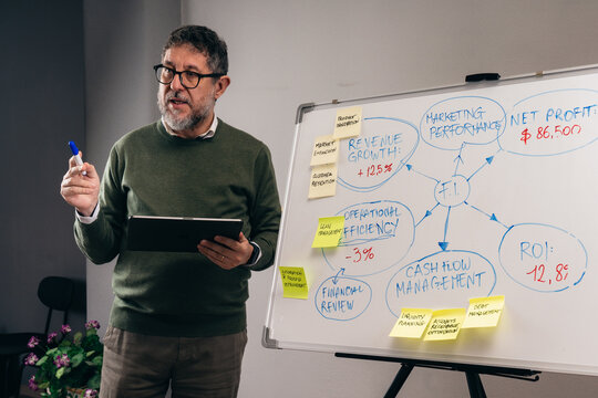 Senior business consultant reviewing financial data on tablet during strategy meeting