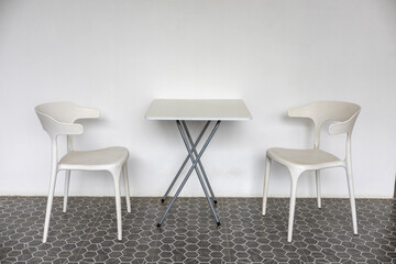 Obraz premium Minimalist white chairs and compact table on patterned tile floor creating modern calm seating scene with soft light and clean lines