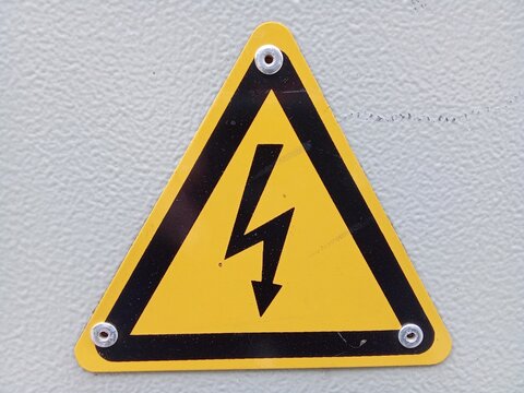 Close-up of yellow triangular sign warning of high voltage electrical hazard