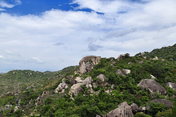 Fototapeta premium Sacred Buddha Carving on Mountain Cliff Surrounded by Green Hills
