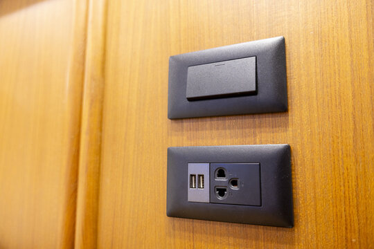 Modern wall switch and dual USB charging outlet mounted on wood panel, functional contemporary interior detail with warm lighting and clean design
