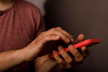 Fototapeta premium A person's hands interact with a bright red smartphone screen.