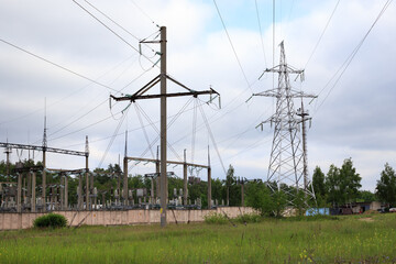 Obraz premium High voltage power lines and electrical substation towers, industrial energy grid infrastructure under cloudy sky background