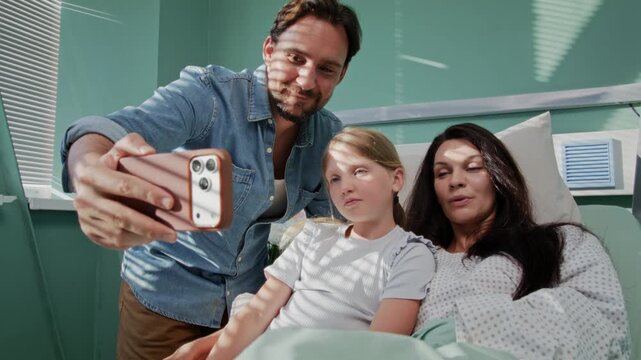 Family takes smiling selfie during hospital recovery visit