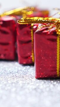 Red present boxes on shiny silver background. Rotate. Christmas and New Year decoration. Vertical footage