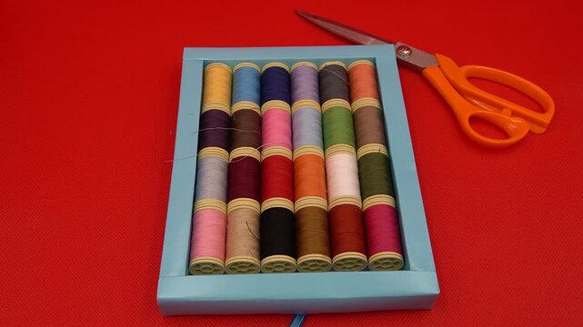 Colorful Sewing Supplies with Threads, Scissors on a Red Background