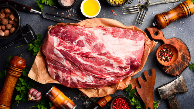Piece of fresh raw pork from the neck, with ingredients and spices on a kitchen background. Meat. Top view. Rustic style.