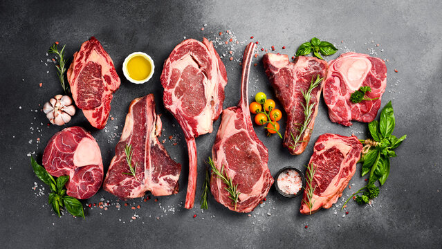 Variety of raw beef meat Prime steaks for grilling with seasoning: Tomahawk steak, Ribeye, T-bone and Ossobuco steak. Meat background.