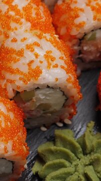 Sushi roll california on black slate plate. Rotate. Vertical footage