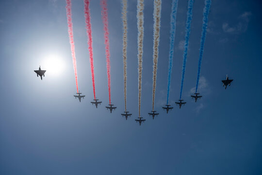 Air show of July 14. 9 Alphajets of the patrol of France in big nine formation and 2 mirage 20000 Ukrainian Air Force flying above the district of La Defense with blue sky and sun background