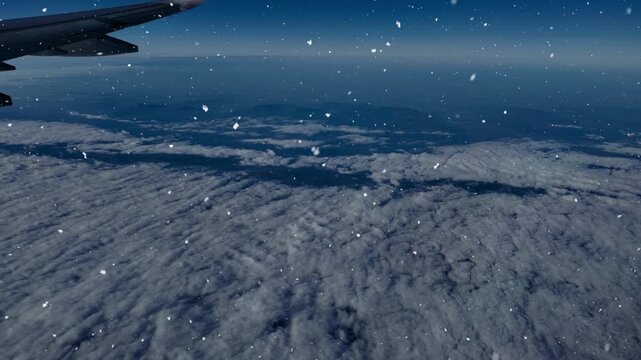 View from an airplane window with the wing above the clouds as snow falls through the sky.