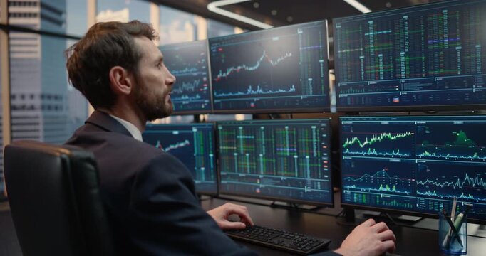Stock Exchange Broker Monitors Financial Data Across a screen Desk, Reviewing Price Charts, Trading Volumes, Investment Analytics for Capital Growth in Finance Office. Moving Camera Focus on Monitors