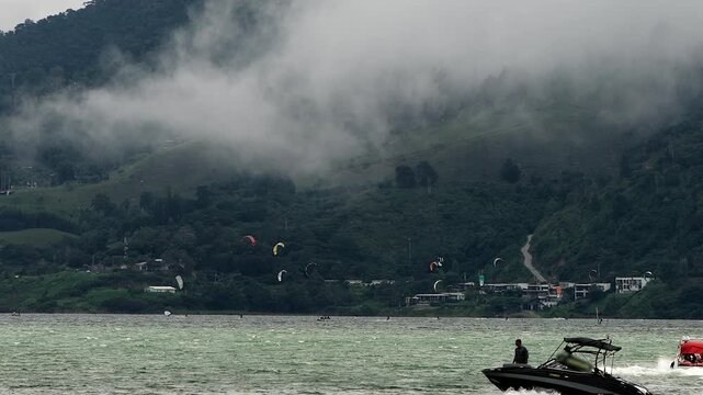 motorboats navigating lake calima with kitesurfers in the background