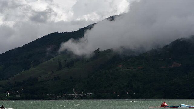 heavy clouds rolling over a green mountain by  lake Calima