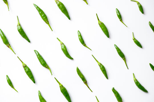 Pattern of fresh green bird's eye chilies or cabe rawit hijau arranged in a grid on white background