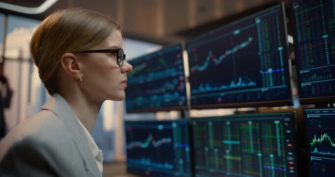 Portrait of Businesswoman Investor Monitors Stock Exchange Feeds Across Wall of Desk Computer Screens, Interpreting Candlestick Graphs, Market Indices and Trading Data to Grow Wealth.