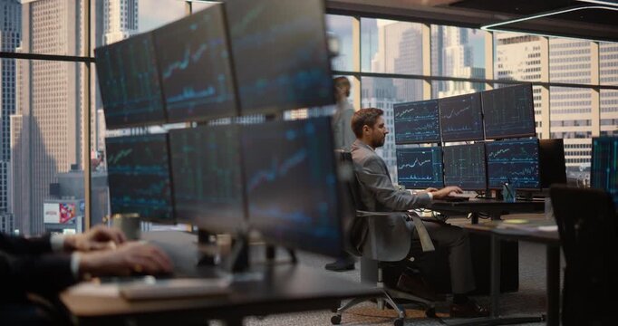 Stockbroker Works at a Desk Analyzing Stock Exchange Market Data, Charts and Graphs on Computer Monitors in Financial Office, Tracking Investment Analytics and Capital Growth. Asset Management Company