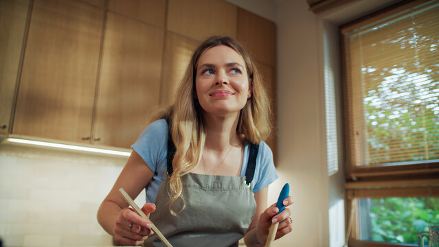 Female social media influencer cooking in the kitchen. Tossing the salad