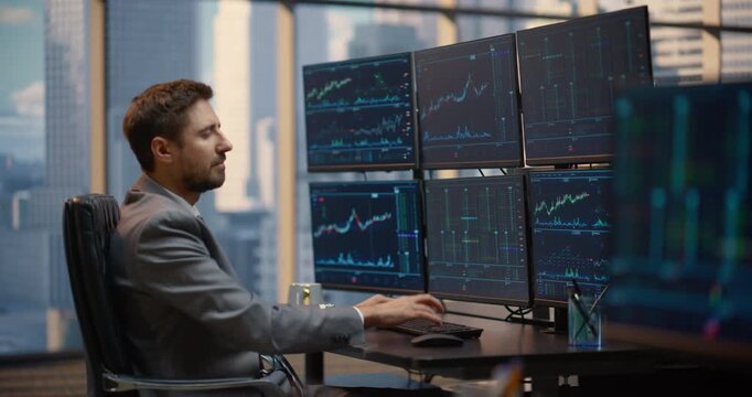 Male Trader Works at His Desk Analyzing Stock Exchange Data, Investment Analytics, and Financial Charts Displayed Across Multiple Monitors, Assessing Market Trends and Capital Growth Opportunities