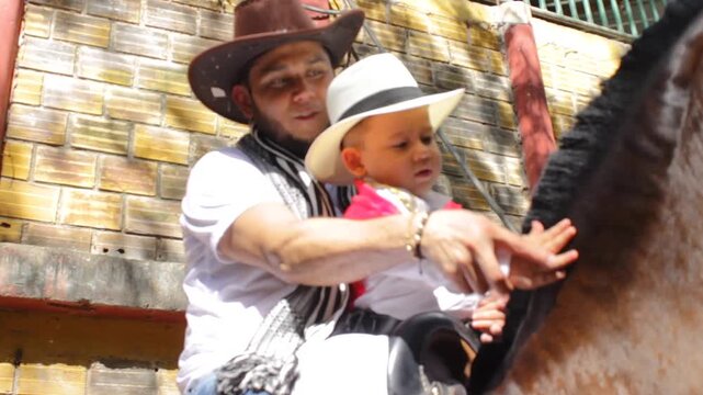 A young father is teaching his young son how to pet a beautiful horse inside a stable in Neiva, Huila, Colombia. Concept of fatherhood and animal themes