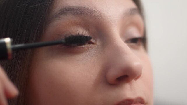 Close-up of a woman combing her eyelashes with a brush to separate them. Close-up of a woman applying mascara to her eyelashes with brush. Beauty routine, eye makeup, and cosmetic care. eye care