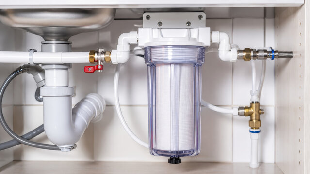 Under-sink water filtration system in a modern kitchen, water purification technology, household appliance, plumbing installation, clean water supply, home improvement, health and safety